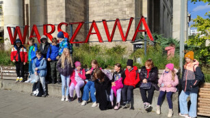 Uczniowie klasy 4b na tle czerwonego napisu Warszawa podczas wycieczki z okazji Dnia Chłopaka